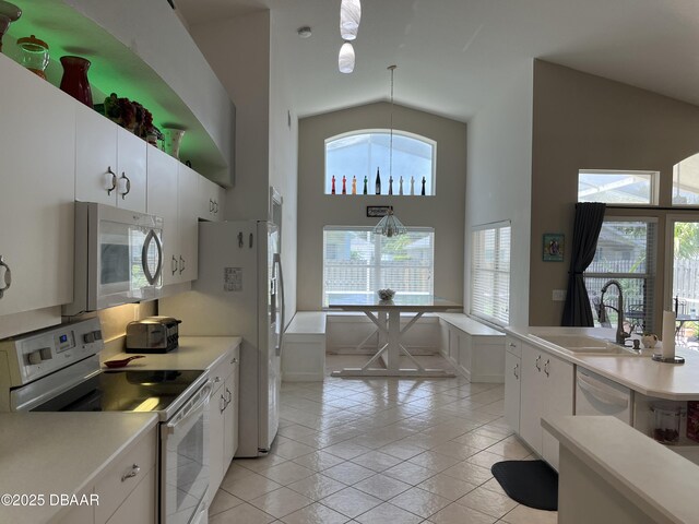5988 Heron Pond Dr, Port Orange, FL 32128 - kitchen with white appliances, light countertops, white cabinets, high vaulted ceiling, and hanging light fixtures