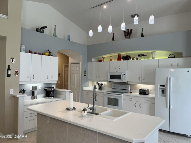 5988 Heron Pond Dr, Port Orange, FL 32128 - kitchen with white appliances, light tile patterned floors, arched walkways, light countertops, and high vaulted ceiling