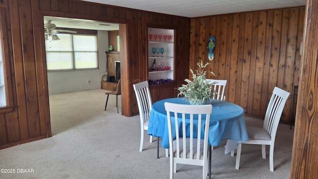 179 Ponce De Leon Dr, Ormond Beach, FL 32176 - carpeted dining room with wood walls, a ceiling fan, and a fireplace with raised hearth