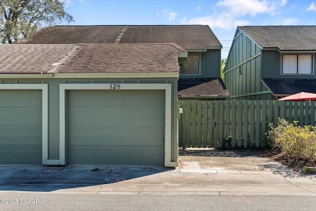 view of front of house with a garage, driveway, a shingled roof, and fence