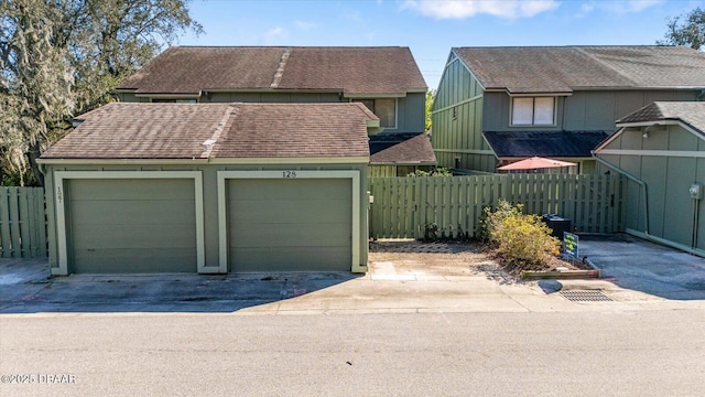 view of front of home featuring a garage, an outbuilding, roof with shingles, and fence