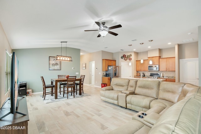 living room with sink, light hardwood / wood-style flooring, vaulted ceiling, and ceiling fan