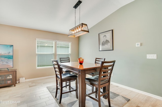 dining space featuring light hardwood / wood-style floors and vaulted ceiling