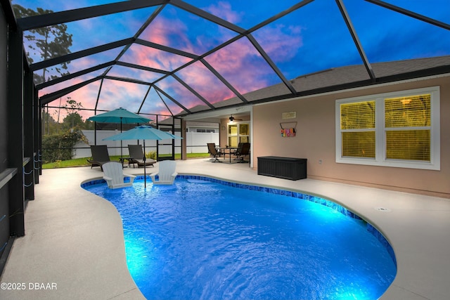 pool at dusk with a lanai, a patio area, and ceiling fan