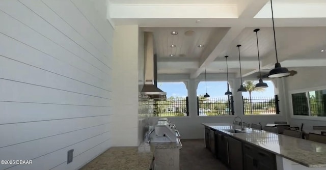 interior space with sink, decorative light fixtures, light stone countertops, and island range hood