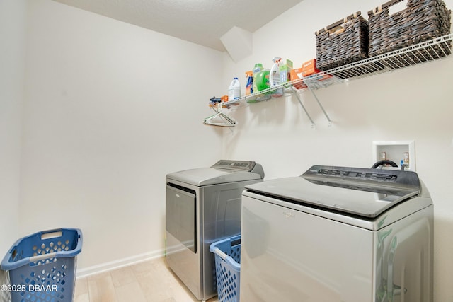 clothes washing area featuring light hardwood / wood-style flooring and washer and dryer