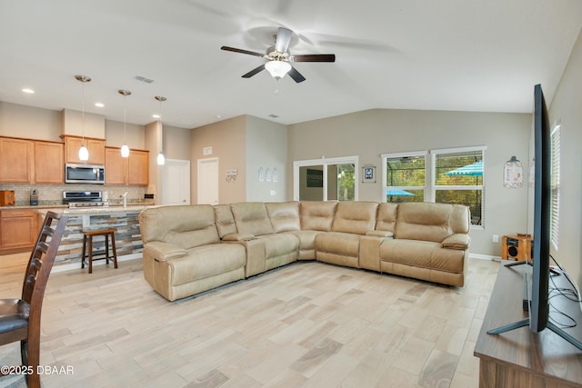 living room with light hardwood / wood-style flooring, vaulted ceiling, and ceiling fan
