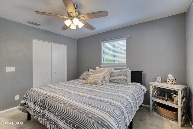 carpeted bedroom with ceiling fan and a closet