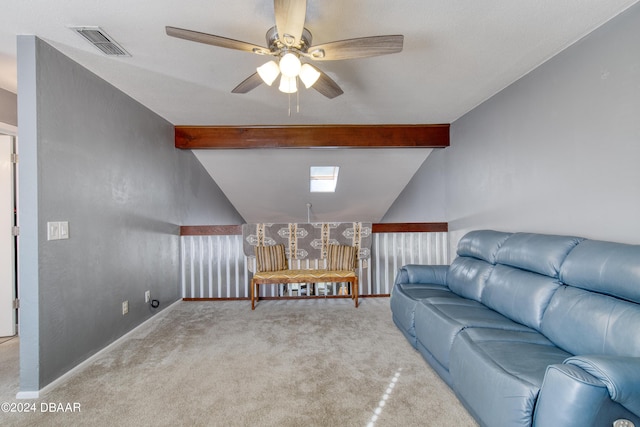 living room with vaulted ceiling with skylight, ceiling fan, and light colored carpet