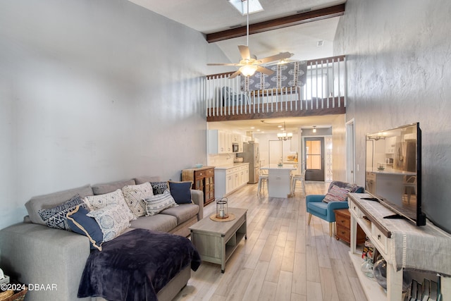 living room featuring beam ceiling, light hardwood / wood-style floors, high vaulted ceiling, and ceiling fan