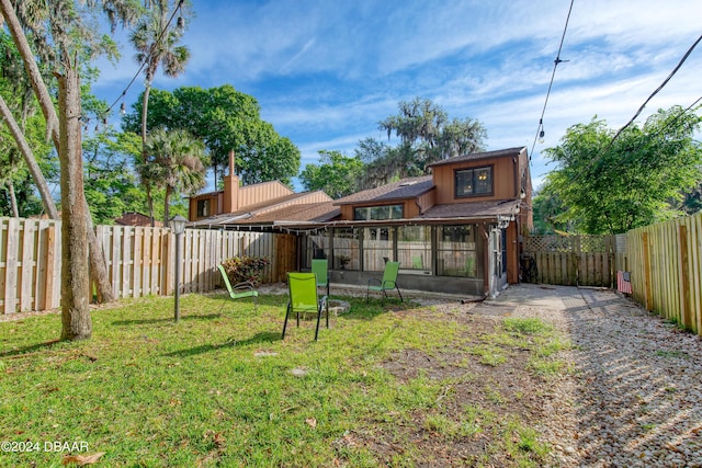 back of house featuring a yard and a sunroom