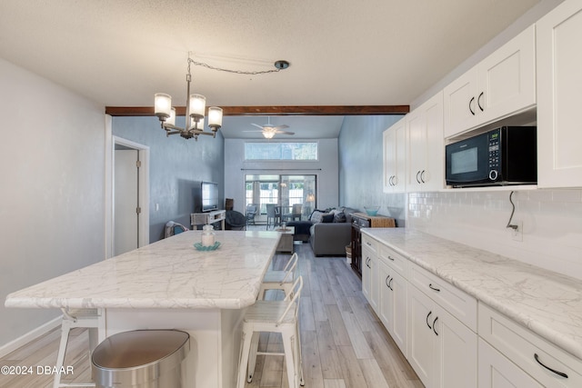 kitchen with a kitchen breakfast bar, white cabinetry, tasteful backsplash, and beam ceiling