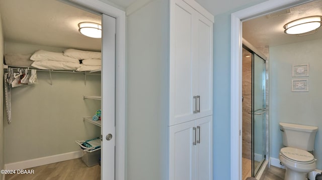 2625 S Atlantic Ave Unit 18Sw, Daytona Beach, FL 32118 - bathroom featuring toilet, a shower with door, and hardwood / wood-style flooring