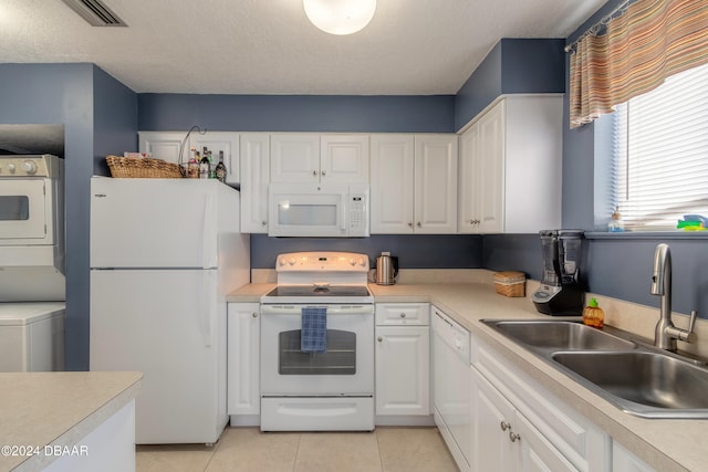 kitchen with stacked washing maching and dryer, white cabinetry, a textured ceiling, sink, and white appliances