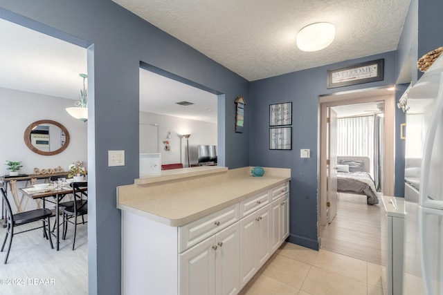 kitchen with white cabinets, washer / dryer, a textured ceiling, and light tile patterned floors