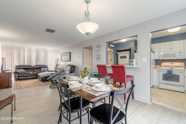 dining space featuring light hardwood / wood-style floors and a textured ceiling