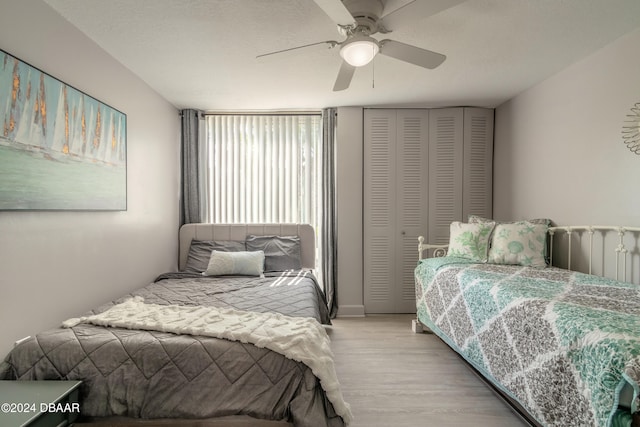 bedroom featuring ceiling fan, a textured ceiling, a closet, and light hardwood / wood-style flooring