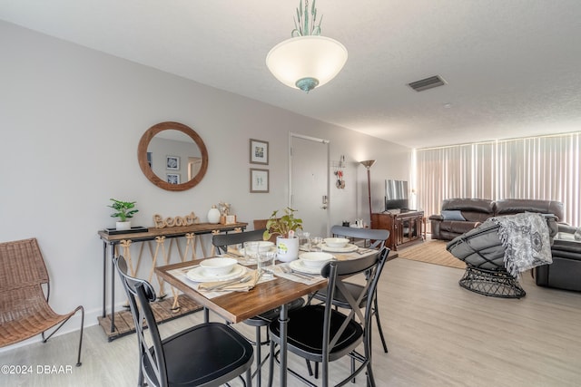 dining area featuring a textured ceiling and light hardwood / wood-style floors