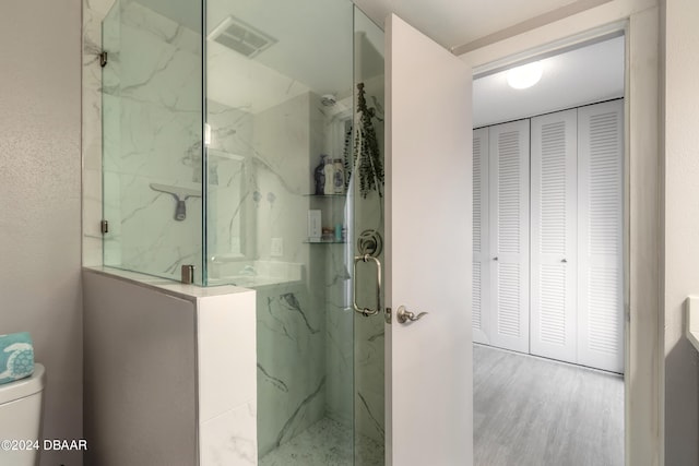 bathroom featuring toilet, hardwood / wood-style flooring, and a shower with shower door