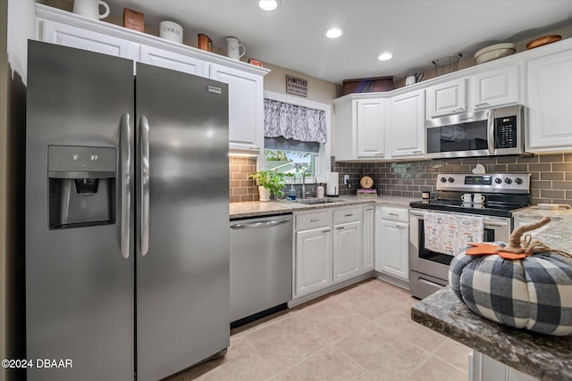 kitchen featuring light stone counters, sink, light tile patterned floors, white cabinetry, and appliances with stainless steel finishes