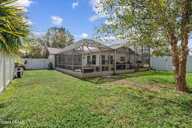 rear view of property featuring a lanai and a lawn