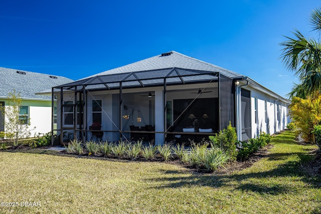 back of property featuring a lawn, ceiling fan, and glass enclosure