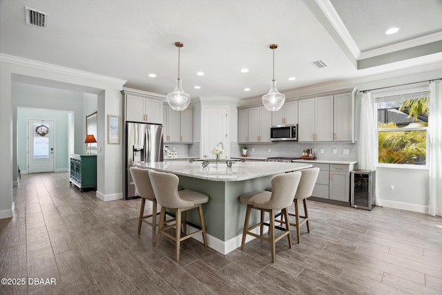 kitchen with appliances with stainless steel finishes, gray cabinetry, pendant lighting, and wine cooler