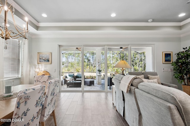 living room featuring hardwood / wood-style flooring, plenty of natural light, a raised ceiling, and ceiling fan with notable chandelier