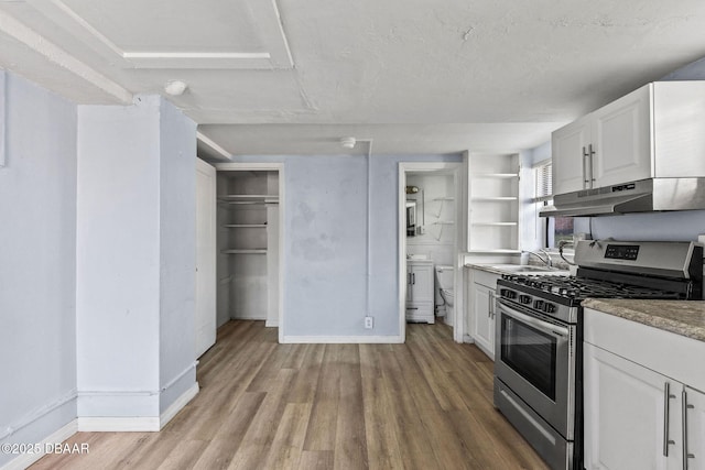 kitchen featuring sink, white cabinets, gas range, a textured ceiling, and light hardwood / wood-style flooring