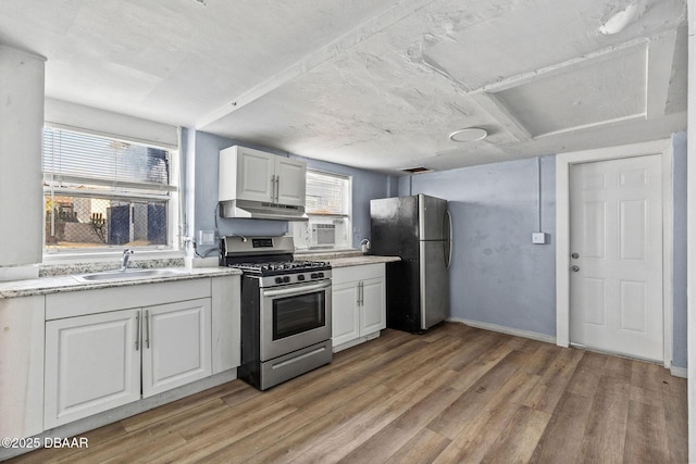 kitchen featuring appliances with stainless steel finishes, sink, white cabinets, and light wood-type flooring