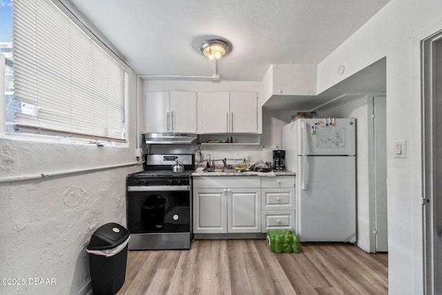 kitchen featuring white cabinetry, sink, white fridge, light hardwood / wood-style floors, and gas stove