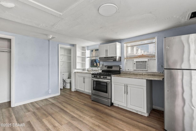 kitchen with sink, cooling unit, white cabinets, stainless steel appliances, and light hardwood / wood-style flooring