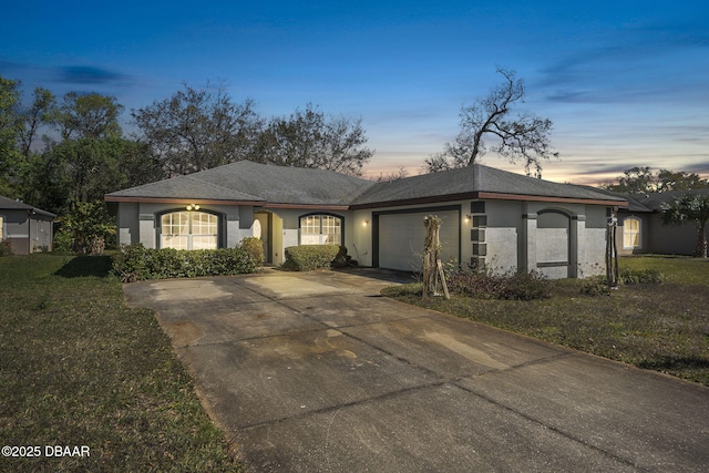 single story home featuring concrete driveway, a yard, an attached garage, and stucco siding