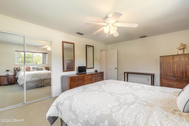 bedroom with a textured ceiling, ceiling fan, light carpet, and a closet