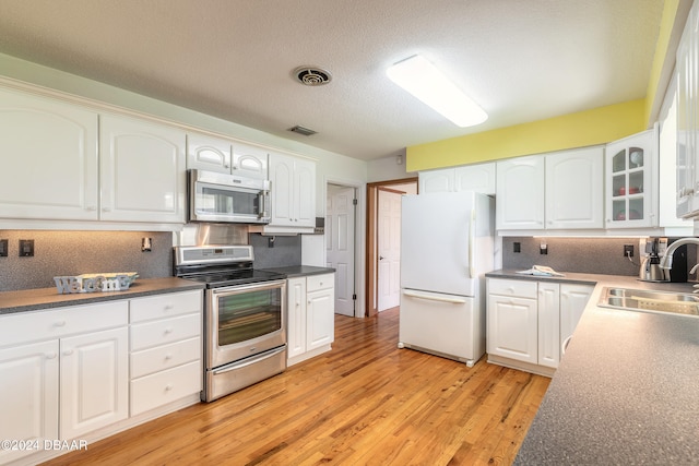 kitchen with white cabinets, sink, light hardwood / wood-style flooring, a textured ceiling, and stainless steel appliances