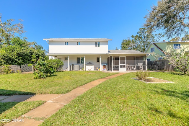 rear view of house with central air condition unit, a lawn, and a sunroom