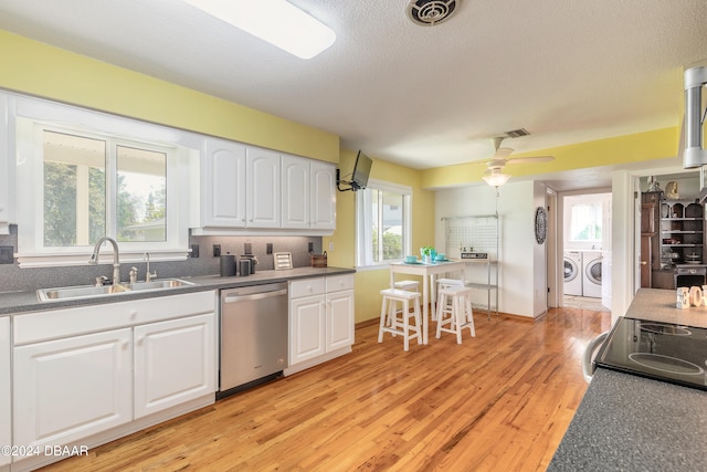 kitchen with dishwasher, sink, washing machine and dryer, white cabinets, and light wood-type flooring