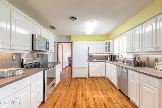 kitchen featuring sink, light wood-type flooring, a textured ceiling, appliances with stainless steel finishes, and white cabinetry