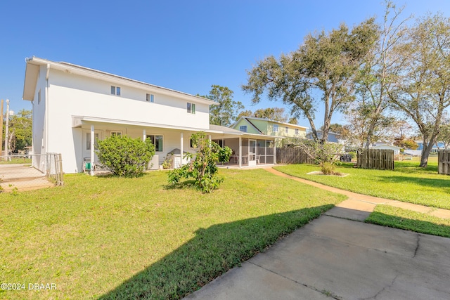 rear view of house featuring a yard and a sunroom