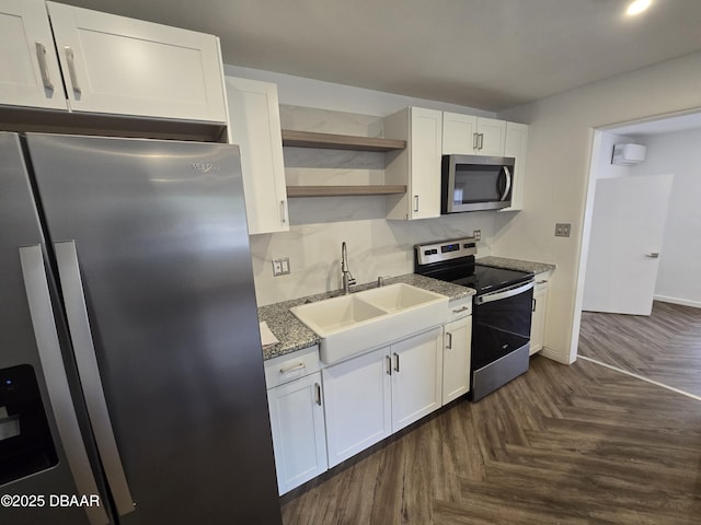 kitchen with sink, appliances with stainless steel finishes, dark parquet floors, stone counters, and white cabinets