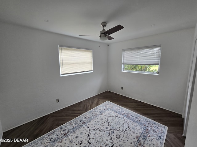 unfurnished room with ceiling fan and dark parquet floors