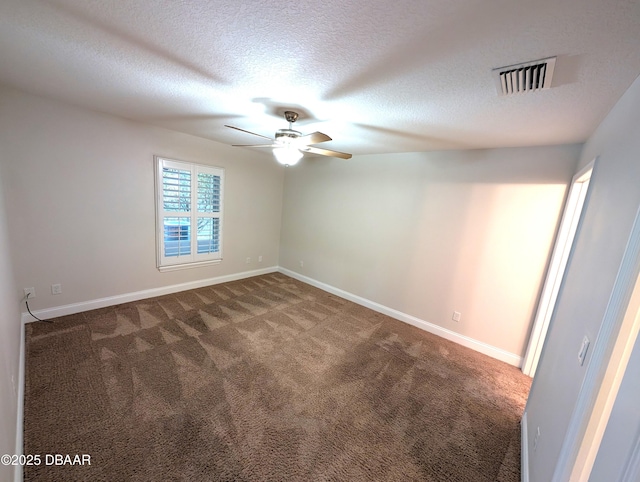 spare room with baseboards, visible vents, dark colored carpet, and a textured ceiling