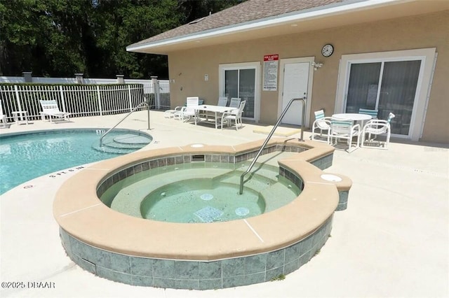 community pool with a patio area, a hot tub, and fence