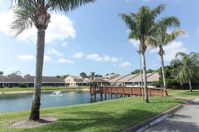 dock area with a water view, a residential view, and a lawn