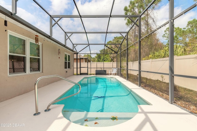 view of pool with glass enclosure, a patio, and a fenced backyard