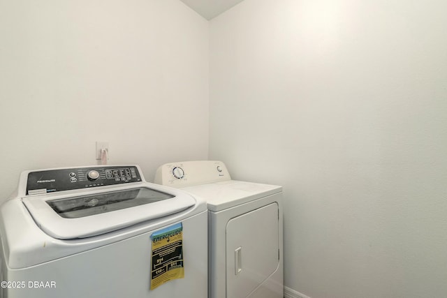 clothes washing area featuring laundry area, washing machine and dryer, and baseboards