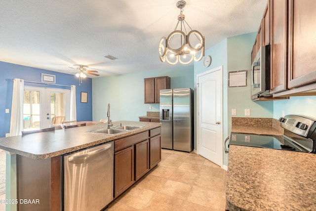 kitchen with visible vents, an island with sink, a sink, french doors, and appliances with stainless steel finishes