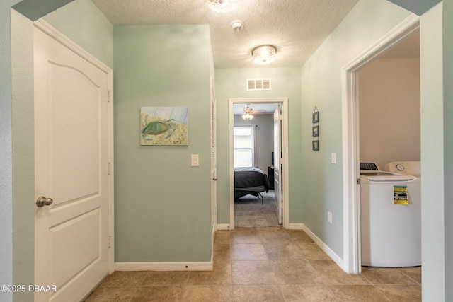 corridor with visible vents, a textured ceiling, washer / clothes dryer, and baseboards