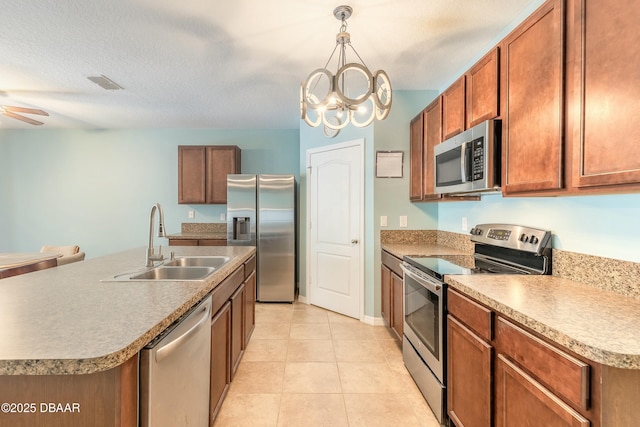 kitchen featuring visible vents, ceiling fan with notable chandelier, a sink, appliances with stainless steel finishes, and brown cabinetry