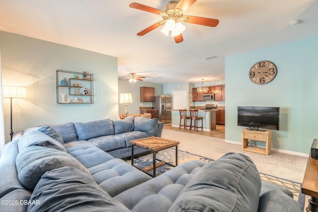 living area with visible vents, baseboards, light colored carpet, and a ceiling fan